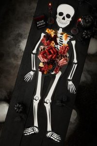 Skeleton serving board with buffet style food resting on the bones 